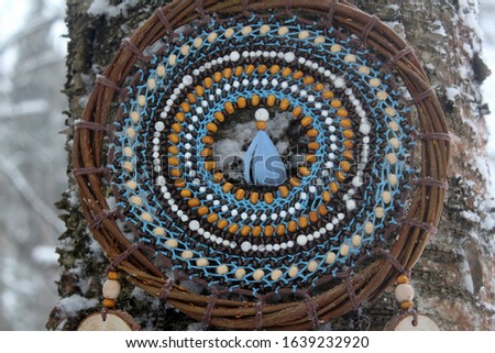 Beautiful dream catcher with blue feathers. Winter time.