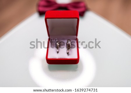 Red box with two golden wedding rings on blurred background, big day concept. Marriage, wedding.