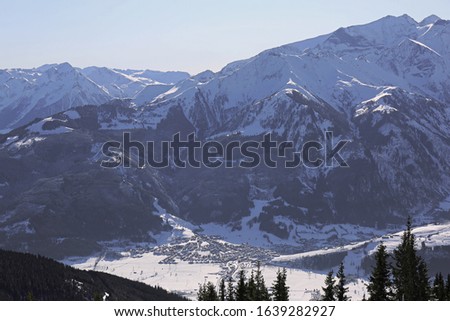 Aerial view of winter Austria valley village from high point of sunny Alp mountains