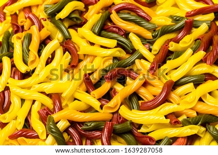 Background of colorful italian pasta. Culinary backdrop, food texture. Table top view. Abstract pattern of multi colored macaroni. Heap of raw pastas s