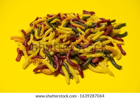 Background of colorful italian pasta. Culinary backdrop, food texture. Table top view. Abstract pattern of multi colored macaroni. Heap of raw pastas