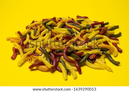 Background of colorful italian pasta. Culinary backdrop, food texture. Table top view. Abstract pattern of multi colored macaroni. Heap of raw pastas.