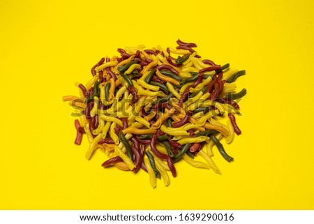 Background of colorful italian pasta. Culinary backdrop, food texture. Table top view. Abstract pattern of multi colored macaroni. Heap of raw pastas d