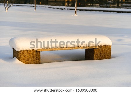 Snow-covered bench in the park. Park bench covered with snow from the first snow fall of the year