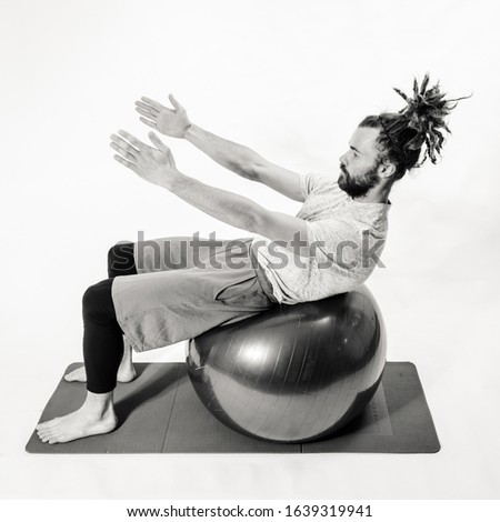 Young man in dreadlocks practicing pilates in studio