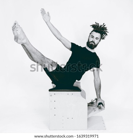 Young man in dreadlocks practicing pilates in studio