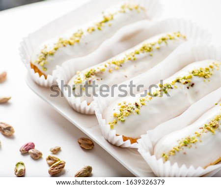 eclairs with white icing and pistachio sprinkles
