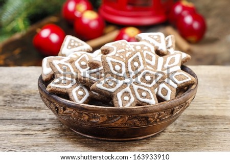 Bowl of gingerbread cookies on rustic grey wooden table, under green fir branch. Copy space.