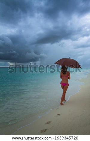 A woman walks on a Maldivian   beach, as the storm approaches.