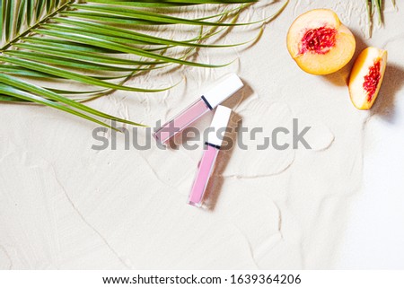 Wonderful beach. Decorative cosmetics, lipstick, lip gloss, lip balm lie on the beach sand, surrounded by juicy fruits, starfish, and palm leaves. Close-up, top view, desktop wallpaper. Copyspace. Royalty-Free Stock Photo #1639364206