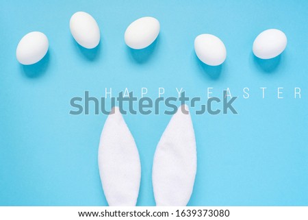 Easter concept. Rabbit ears and white eggs. On a blue background.
