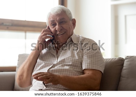 Happy mature man sit on couch at home talking on cellphone with fast unlimited mobile provider connection, smiling elderly male senior grandfather have call with relatives use smartphone internet Royalty-Free Stock Photo #1639375846