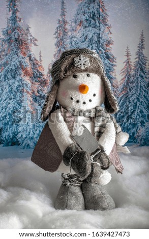 An adorable stuffed snowman stands against a snowy winter background, clutching a wooden sled