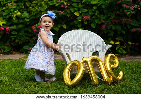 Beautiful one year old baby girl portrait in a home garden setting.