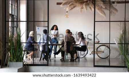Diverse businesspeople negotiating at group meeting led by african woman leader gathered together in office modern interior rich corporation. Client and boss discuss project, coach teach staff concept Royalty-Free Stock Photo #1639493422