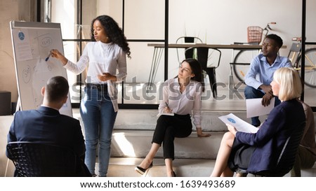 Focused staff comfortably settled in modern office attending at workshop in informal setting listen african trainer teaching audience share ideas finance plan use flip chart, mentoring seminar concept Royalty-Free Stock Photo #1639493689