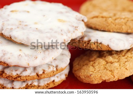 Pile of oatmeal cookies with sugar icing on red plate background