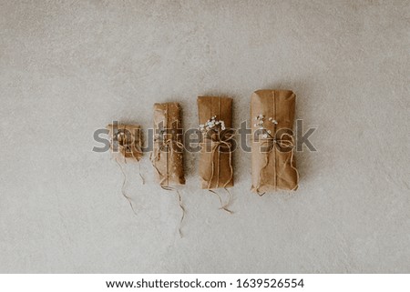 Gift wrapped in paper with dried flower and string on marble background