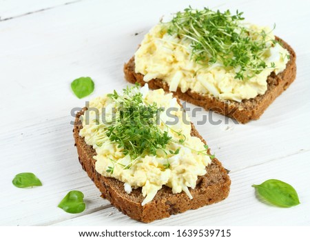 Egg salad over brown bread with garden cress. White background.  Homemade spread made from eggs, mayonnaise and mustard. Royalty-Free Stock Photo #1639539715