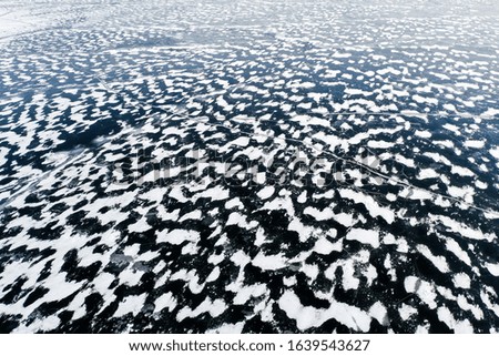 Aerial view of a frozen lake surface. Aerial Snow pattern on the frozen lake. Frozen lake ice captured with a drone. Aerial photography. Winter snow texture