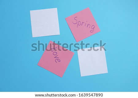 notes with the inscriptions love, spring on a blue background. copy space