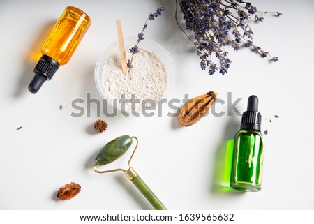Close up of white clay, lavender, bottles of vitamin serum and massage roller stock photo