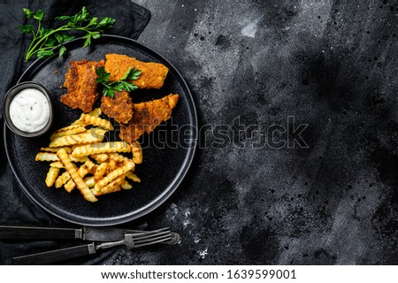 fish and chips, french fries served with sauce. Black background. Top view. Copy space