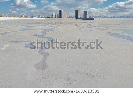 Roofing membrane after the rain, against the backdrop of the city. Water on the roof of the membrane. Royalty-Free Stock Photo #1639613581