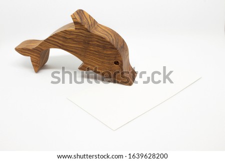 Business card on a white background next to a wooden dolphin