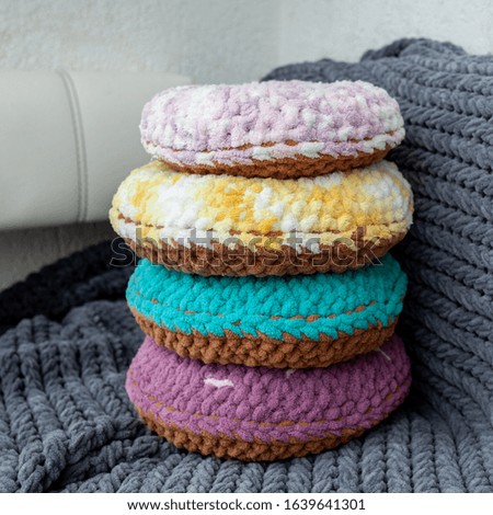 Colored decorative pillows in the form of donuts on a gray plaid background