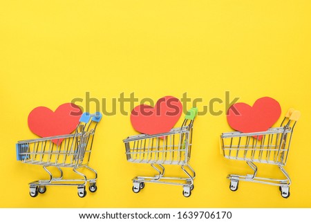 Paper hearts with shopping carts on yellow background