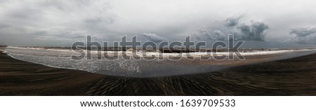Stormy weather on the beach, the waves crash on the shore leaving their mark, overcast sky with beautiful cumulus clouds rain, spreads a melancholic atmosphere
