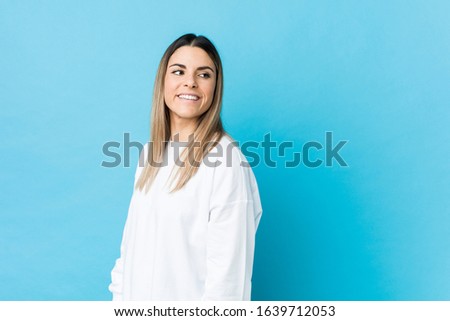 Young caucasian woman isolated looks aside smiling, cheerful and pleasant.