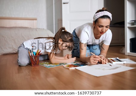 beautiful mommy and her kid paintig a picture for kindergardern. hobby, education, development , child developing painting skills. close up photo