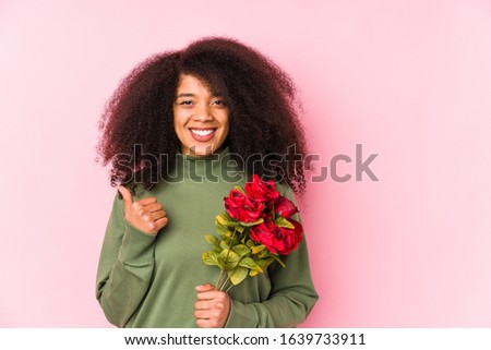 Young afro woman holding a roses isolated Young afro woman holding a rosessmiling and raising thumb up