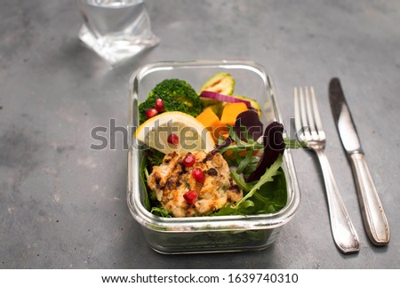 Healthy lunch box container  with grilled chicken meatballs, broccoli, zucchini, pumpkin and salad on grey background selective focus.