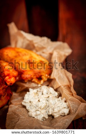 kibbeling, traditional cod fish from the Netherlands with tartar sauce in paper on rustic background