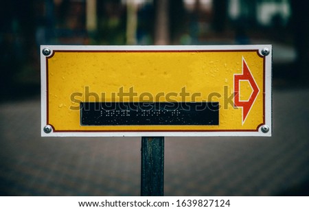 Yellow plate for your text with dots for reading by hands for the blind. Signpost sign for the blind and disabled. Signpost sign in the park for your text. out of focus Copy Space