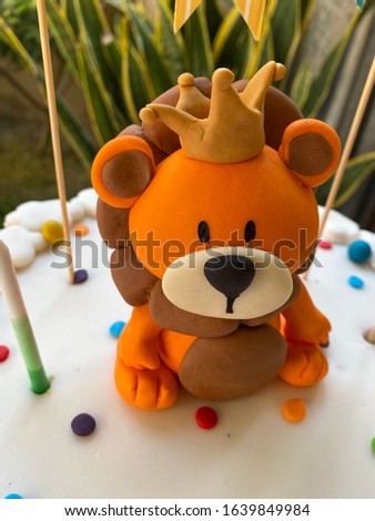 Lion with a crown made of orange fondant on a birthday cake.
