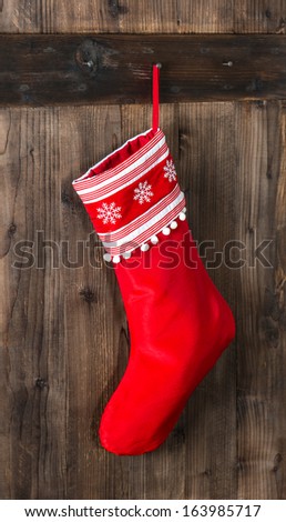 red christmas sock with snowflakes for Santa gifts hanging on wooden background. holidays symbol stocking
