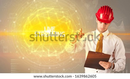 Handsome businessman with helmet drawing LIVE STREAMING inscription, social construction concept