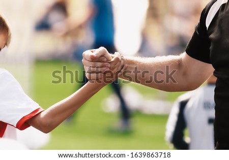Soccer football kids player and junior team coach congratulating after the match. Greeting after soccer game. Trainer and child shaking hands after playing tournament match Royalty-Free Stock Photo #1639863718