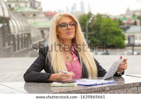 Young Blond Business Woman In red Suit Holding The smartphone In Her Hand Standing in downtown