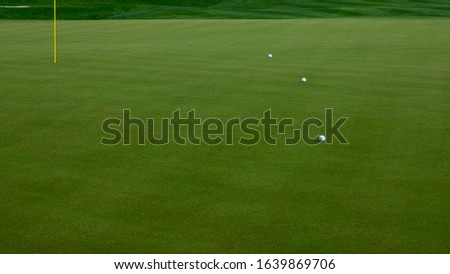 Golfballs on the green near the pole
