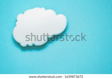 Decorative interiour white clear cloud lamp hangs on a textural blue wall representing a clear sky. Background texture. Copy space for your text.