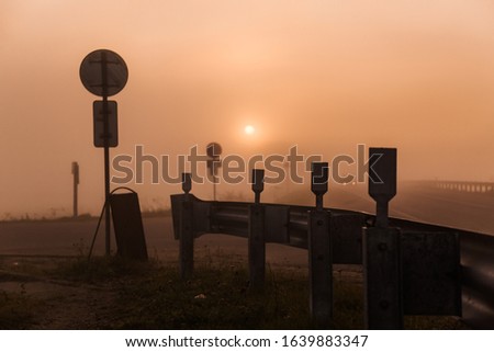 Sunrise and fog on the track, in the distance you can see the headlights of a passing car, landscape moment. Hitchhiking.