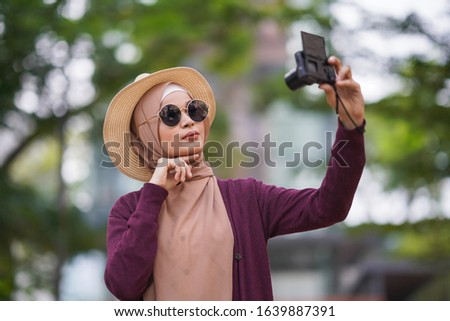 Portrait of beautiful young solo Muslim traveler taking self photo (selfie)