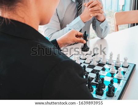 Two business people are planning business strategies through playing chess to make the business go according to plan.
