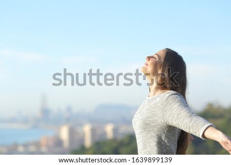Profile of a woman breathing deeply fresh air with a city in the background Royalty-Free Stock Photo #1639899139