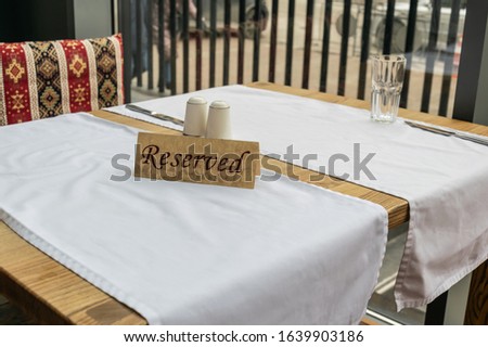 The plate is reserved on a table with white tablecloths in a cafe or restaurant. Table setting.